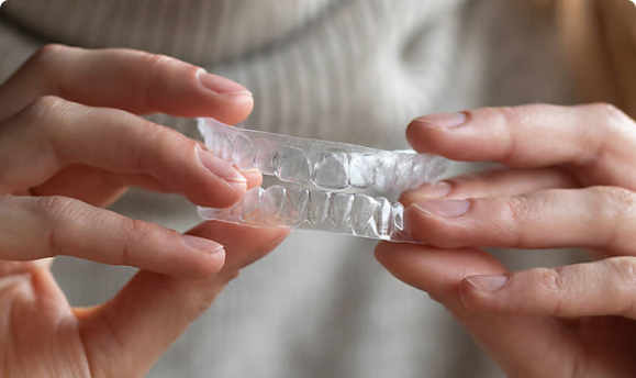 A clear aligner held in a hand
